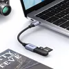 A Ugreen USB-C to USB-A OTG adapter with an SD and MicroSD card slot is connected to a laptop, with a camera lens and a book in the foreground. Podgląd zdjęcia produktu