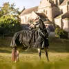 A horse wearing a black and gold turnout blanket stands in a grassy field in front of a stone building. Voir les images du produit