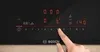 A finger is shown pressing buttons on a black induction cooktop. Produktbild-Vorschau