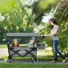 A woman pushing a wagon with two children in it, outdoors in a park. Náhled obrázku produktu