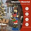 A large illuminated nutcracker figure with a drum, decorated for Christmas, stands outdoors in the snow next to a Christmas tree and outdoor furniture. Text overlays highlight its all-weather material and features like being waterproof, snowproof, windproo Podgląd zdjęcia produktu