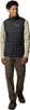 A man wearing a black vest over a tan long-sleeved shirt and brown pants, standing against a white background. Voir les images du produit