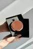 Hands holding a rose gold flask in a black box, with shadows cast on a white wall. Náhľad obrázku produktu