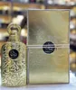 A gold-colored perfume bottle and its matching box are displayed side-by-side. Podgląd zdjęcia produktu
