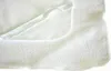 A close-up view of a white fabric product, possibly a mattress protector or bedding, showing its textured surface and a folded edge with elastic. Produktbild-Vorschau