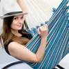 A woman is relaxing in a striped hammock chair. Anteprima dell’immagine prodotto