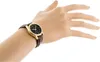 A woman's hand wearing a gold-cased watch with a brown leather strap. Produktbild-Vorschau