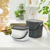 Two compost bins are placed on a kitchen counter next to a sink and some asparagus. Voir les images du produit