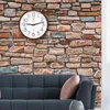A clock is mounted on a stone wall above a sofa. Voir les images du produit