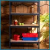 A metal shelving unit with various items on its shelves, including jars, apples, and storage bins, set against a wooden hexagonal wall. Podgląd zdjęcia produktu