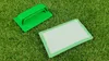 Two green cleaning tools are placed on a grassy surface. Produktbild-Vorschau