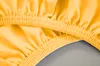A close-up view of a yellow fitted sheet with elasticized edges. Produktbild-Vorschau