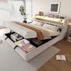 A bedroom scene featuring a hydraulic storage bed with its storage compartment open, revealing stored items. The bed is made up with bedding and pillows, and the headboard has integrated lighting. Náhled obrázku produktu
