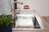 A stainless steel kitchen sink with a faucet, a bowl of tomatoes, and a potted plant. Produktbild-Vorschau