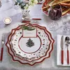 A festive Christmas table setting with plates, cutlery, a wine glass, and a candle. Anteprima dell’immagine prodotto