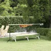 A rotisserie grill with meat cooking on it, set up on a grassy lawn in a garden setting. Produktbild-Vorschau