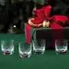 Four small glasses are arranged on a green tablecloth in front of a Christmas gift and a Christmas tree. Náhled obrázku produktu