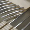A close-up view of several stainless steel forks and knives neatly arranged in a wooden cutlery organizer. Produktbild-Vorschau