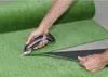 A person is cutting artificial grass with an electric shear. Produktbild-Vorschau