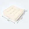 A square cushion with tufted detailing and a handle, shown on a white background with dimension lines indicating its size. Produktbild-Vorschau