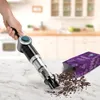 A hand holding a cordless vacuum cleaner is cleaning up spilled coffee grounds on a marble countertop in a kitchen setting. Produktbild-Vorschau