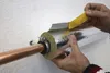 A person is insulating a copper pipe with a silver-colored insulation material and yellow tape. Produktbild-Vorschau