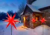 A stone cottage with a snowy roof and yard, decorated with red star-shaped lights. Produktbild-Vorschau