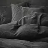 A close-up view of dark gray bedding, including pillows and a duvet. Produktbild-Vorschau