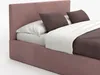 A close-up view of a pink upholstered bed with white and brown bedding and pillows. Náhľad obrázku produktu
