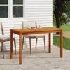 A wooden garden table and chairs set on a patio next to a house. Náhled obrázku produktu