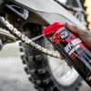 A hand is spraying lubricant onto a motorcycle chain. Produktbild-Vorschau