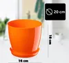 An orange plastic plant pot with a saucer, shown on a table with a blurred background. Náhľad obrázku produktu