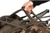 A hand is shown holding the straps of a folded brown camouflage chair. Produktbild-Vorschau
