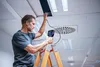 A man on a ladder inspecting a ceiling with a camera. Anteprima dell’immagine prodotto