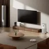 A modern living room with a large TV, a floor fan, an air purifier, a coffee table, and a robot vacuum cleaner. Náhľad obrázku produktu
