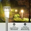 A solar garden light in a garden setting at dusk, with other lights in the background. Produktbild-Vorschau