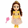 A doll resembling Disney's Belle from Beauty and the Beast, dressed in her iconic yellow ball gown, stands against a white background. A small pink accessory, possibly a mirror, is placed to the left of the doll. Anteprima dell’immagine prodotto