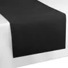 A black table runner is laid diagonally across a white surface, likely a table. Náhľad obrázku produktu