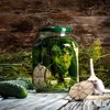 A jar of pickles with garlic and dill on a wooden table. Podgląd zdjęcia produktu