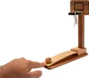 A hand is about to launch a small wooden ball on a ramp towards a miniature basketball hoop. Podgląd zdjęcia produktu