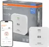 The image shows the packaging of an OSRAM Smart+ CO detector, along with a smartphone displaying the device's app interface and a separate detector unit. Produktbild-Vorschau