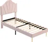 A pink upholstered bed frame with a shell-shaped headboard and gold legs, shown from a diagonal angle against a white background. Produktbild-Vorschau