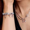 A close-up shot of a person's arm and neck, showcasing a Pandora charm bracelet and necklace with Disney-themed charms. Voir les images du produit
