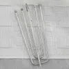 A close-up overhead view of several metal curtain hooks resting on a white textured fabric. Produktbild-Vorschau