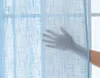 A hand is shown touching a light blue translucent curtain. Produktbild-Vorschau