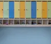 A row of colorful lockers with shoe cubbies below, containing various shoes. Podgląd zdjęcia produktu