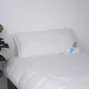 A white pillow on a white bed with a white wall in the background. Produktbild-Vorschau