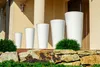 A set of five white planters of varying sizes are displayed on a stone ledge in front of a building. Anteprima dell’immagine prodotto