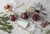 A festive arrangement of jam jars, cheese, bread, and spices, suggesting a holiday or gourmet food setting. Produktbild-Vorschau