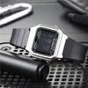A digital watch is placed on a textured surface, with other objects in the background. Anteprima dell’immagine prodotto